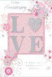 This anniversary card offers a gentle celebration of lasting romance, its colours and textures harmonising the way a well-balanced bouquet does on our Castelnau workbench. The background is bathed in soft pastel pinks and silvery greys, creating a hushed, intimate atmosphere reminiscent of an early morning stroll by the Thames before the streets fully wake. At the heart of the design, the word LOVE is spelled out in softly raised glitter, each letter delicately edged so it can be felt as much as seen. The O is transformed into a shimmering silver heart, textured to sparkle like light catching on a polished vase in a florist's window. Around this focal word, graceful blooms in blush and mauve unfurl, painted with an almost watercolour softness that suggests the petals might rustle if you brushed them. Their fine, flowing outlines and subtle shading recall the natural curves of roses and sweet peas. Tiny flourishes - scattered petals, scrolling lines, and the faint suggestion of butterflies - add a sense of motion and whimsy, like a breeze drifting through a garden in nearby Barnes Common. Elegant scripts carry the phrases On Our Anniversary and I love you today and always, their flowing lines echoing the curls of the illustrated vines. Nothing about the design is loud; instead, it whispers of shared years and quiet devotion, the same sentiment that often accompanies our anniversary flower deliveries across Castelnau, Barnes, and Mortlake. The card feels like a keepsake meant to be cherished in a drawer or memory box long after the day itself has passed.